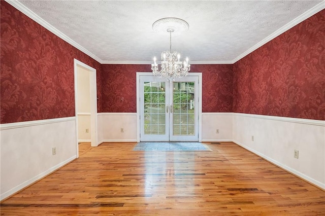 5247 Yeager Rd, Douglasville, GA 30135 - unfurnished dining area with wood finished floors, a chandelier, french doors, a textured ceiling, and a wainscoted wall