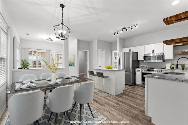 dining area featuring light hardwood / wood-style floors, sink, and a chandelier