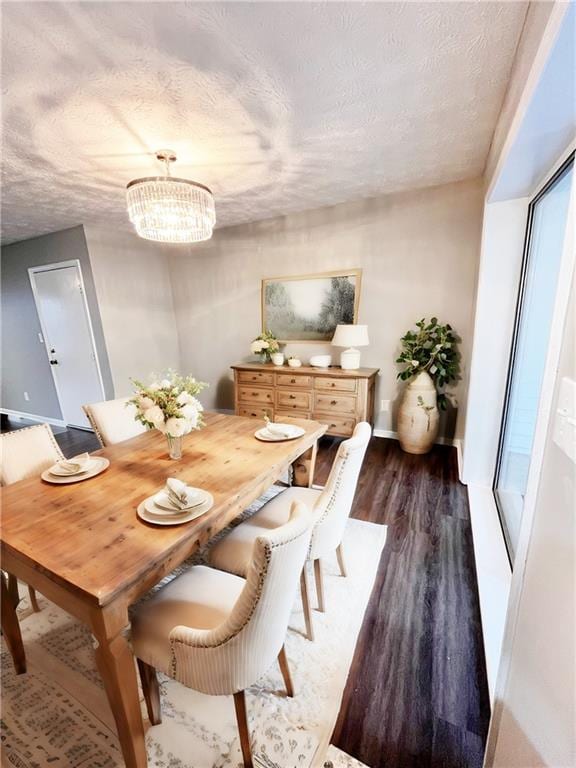 dining space with a textured ceiling, a notable chandelier, and dark wood-type flooring