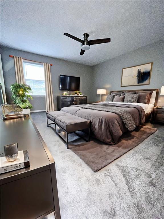 carpeted bedroom with ceiling fan and a textured ceiling