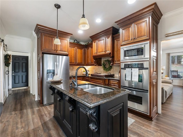 kitchen featuring an island with sink, sink, appliances with stainless steel finishes, dark hardwood / wood-style floors, and a barn door