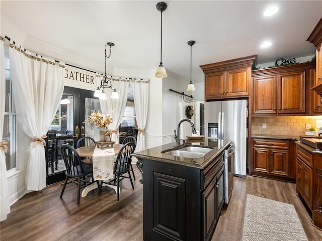 kitchen featuring a center island with sink, dark hardwood / wood-style flooring, pendant lighting, and plenty of natural light