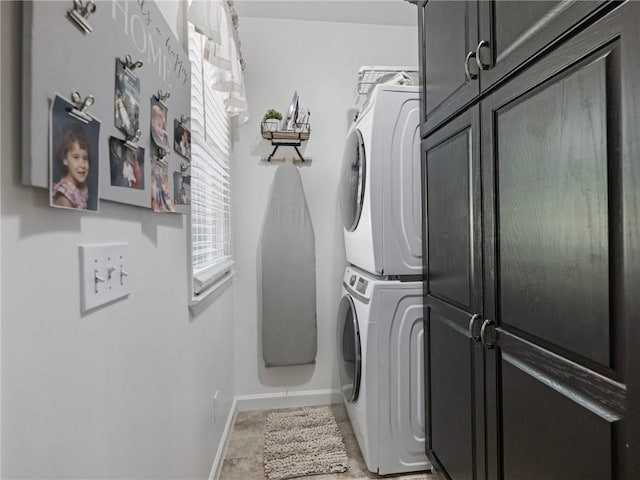 laundry area with cabinets, stacked washer / dryer, and tile patterned flooring