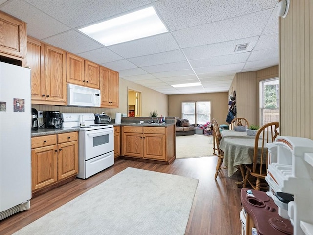 kitchen featuring sink, kitchen peninsula, white appliances, wood-type flooring, and a paneled ceiling