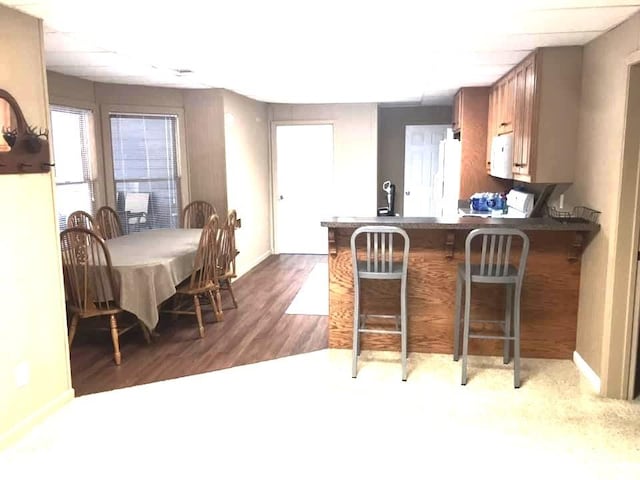 kitchen featuring white appliances, kitchen peninsula, a breakfast bar area, and dark hardwood / wood-style flooring