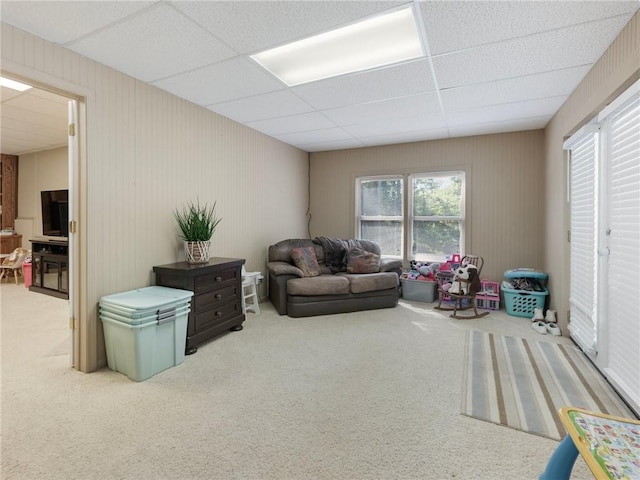 carpeted living room featuring a drop ceiling