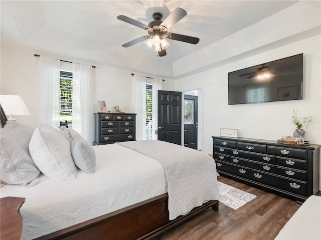 bedroom with a tray ceiling, dark hardwood / wood-style flooring, and ceiling fan