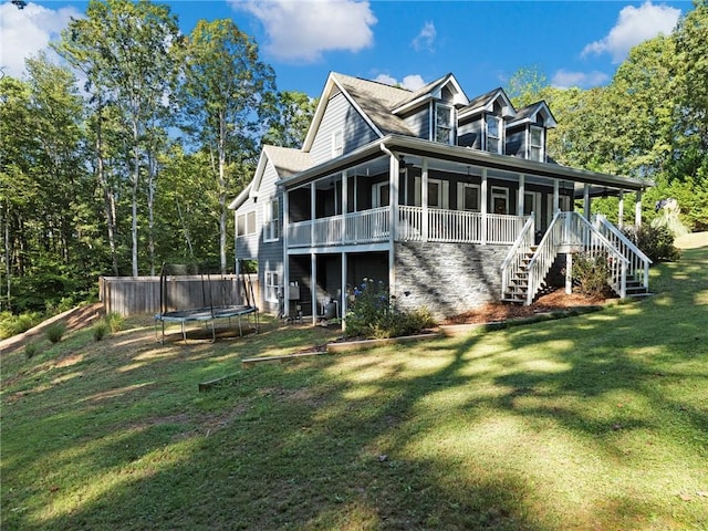 back of house with a lawn, a trampoline, and a sunroom