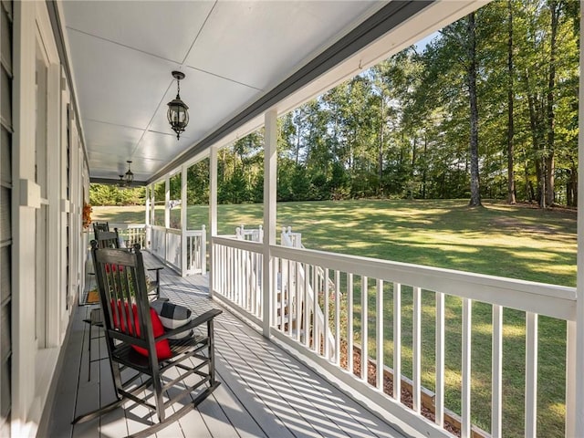 wooden deck featuring a porch and a lawn