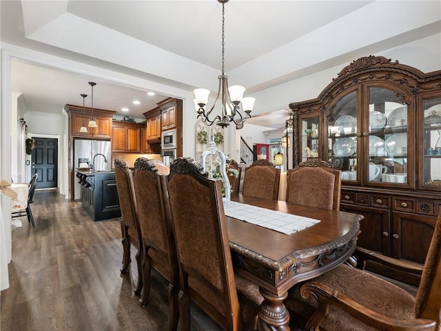 dining space with a notable chandelier, a tray ceiling, and dark wood-type flooring