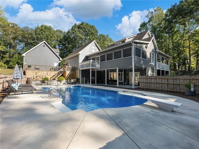 view of swimming pool featuring a diving board, a deck, a sunroom, and a patio area