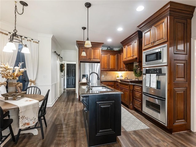 kitchen with dark hardwood / wood-style floors, sink, a barn door, stainless steel appliances, and a center island with sink