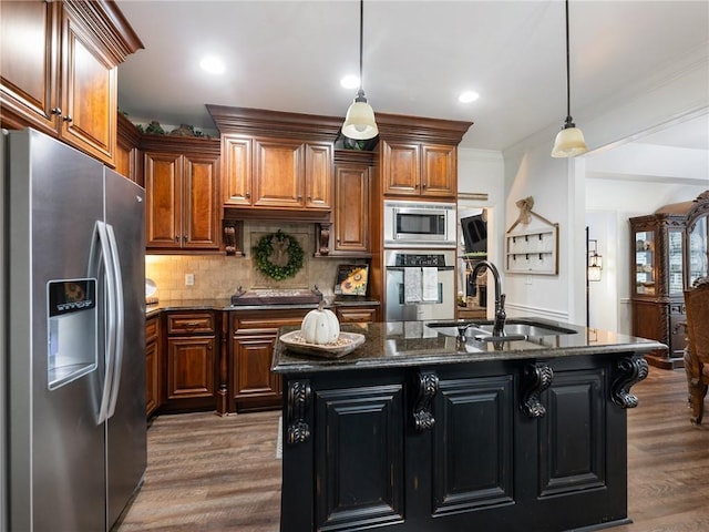 kitchen featuring pendant lighting, an island with sink, sink, dark wood-type flooring, and stainless steel appliances