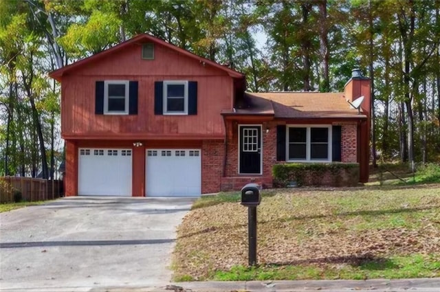 split level home featuring driveway, a garage, a chimney, fence, and brick siding