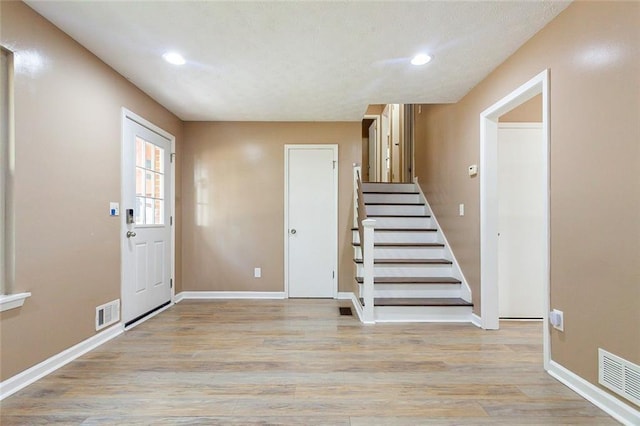 foyer featuring light wood-type flooring, visible vents, baseboards, and recessed lighting