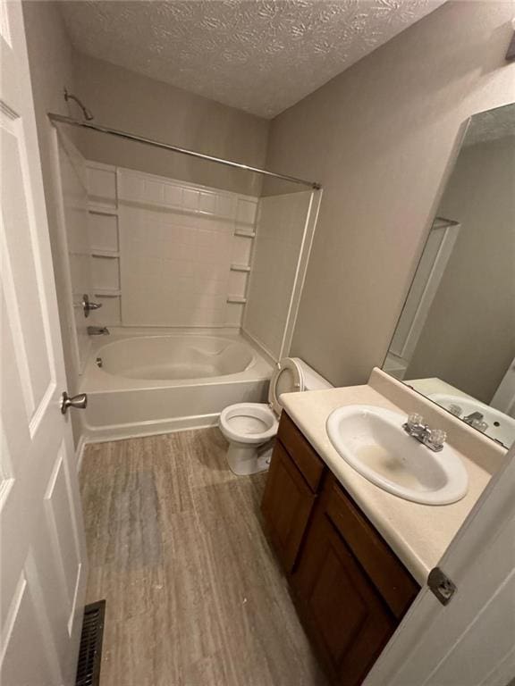 full bathroom with a textured ceiling, washtub / shower combination, vanity, toilet, and hardwood / wood-style flooring