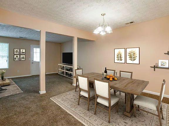 carpeted dining space featuring a notable chandelier and a textured ceiling