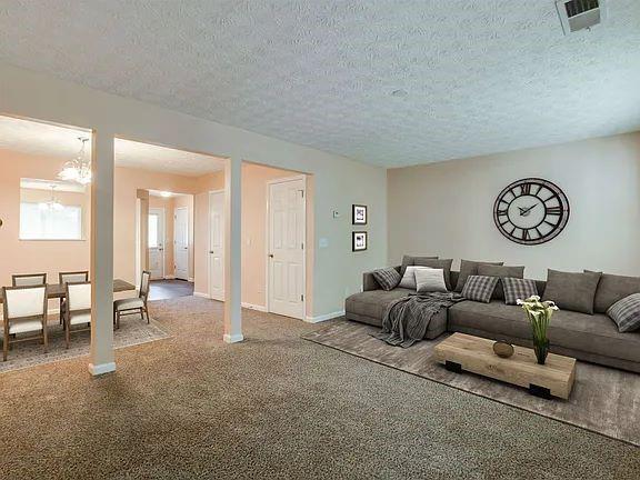 carpeted living room featuring a textured ceiling and an inviting chandelier