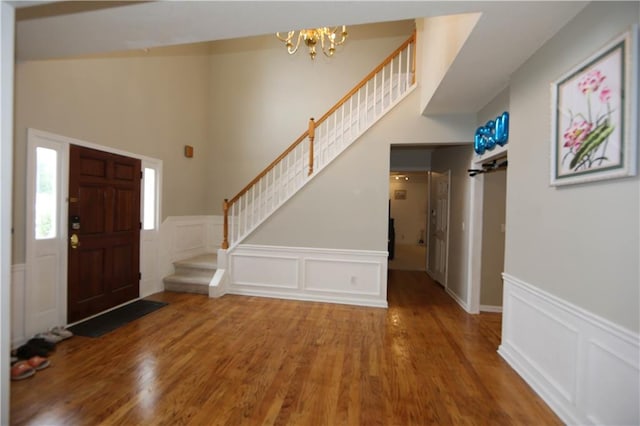 foyer featuring a towering ceiling, a chandelier, and hardwood / wood-style flooring