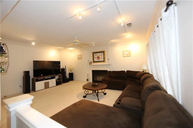 carpeted living room featuring ceiling fan, crown molding, and rail lighting