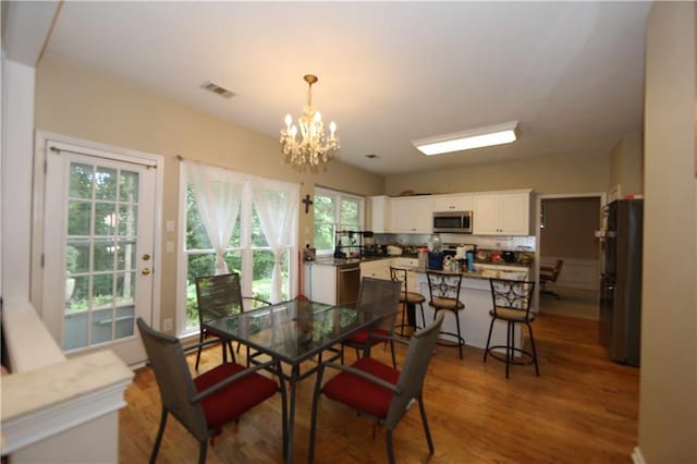 dining room with wood-type flooring, a notable chandelier, and a wealth of natural light