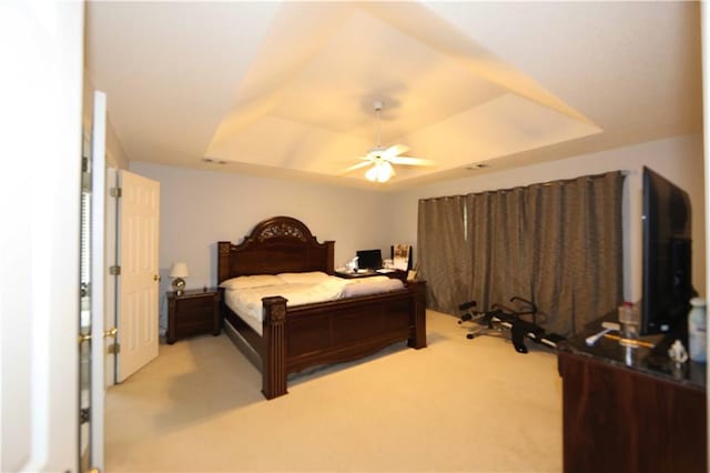 carpeted bedroom with ceiling fan and a tray ceiling