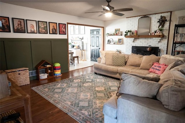 living room featuring dark hardwood / wood-style flooring, a fireplace, and ceiling fan