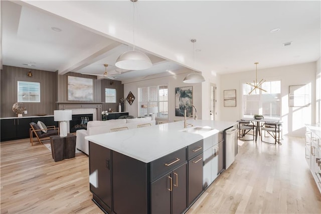 kitchen with dishwasher, an island with sink, sink, and pendant lighting