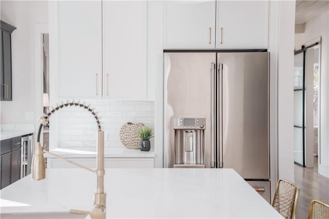 kitchen with a barn door, high end refrigerator, and white cabinets