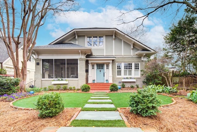 view of front of property featuring brick siding, a front lawn, fence, and a sunroom