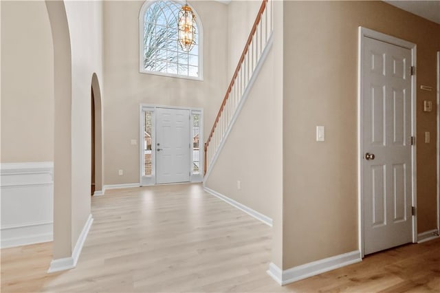 entryway with a notable chandelier, light hardwood / wood-style floors, and a high ceiling