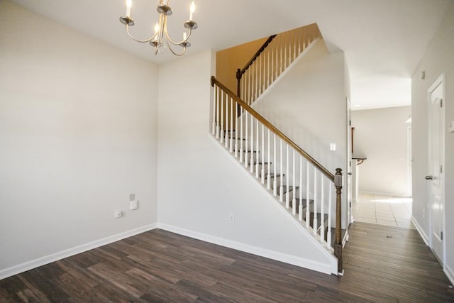 stairs featuring an inviting chandelier, baseboards, and wood finished floors