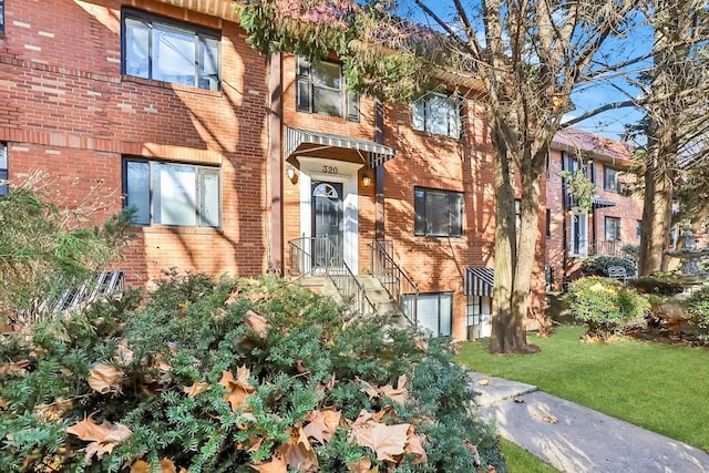 view of front of house featuring brick siding and a front yard