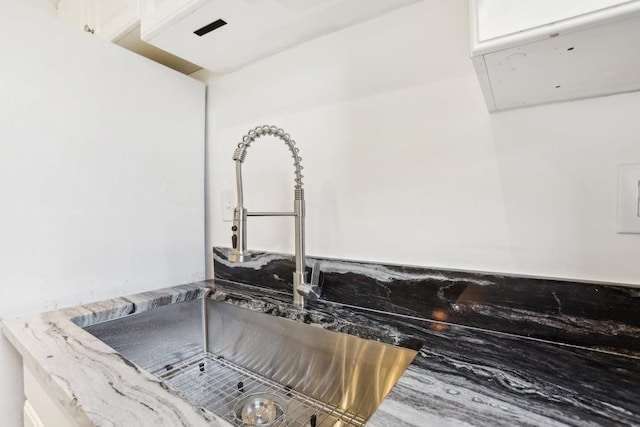 room details with white cabinets, sink, and stone counters