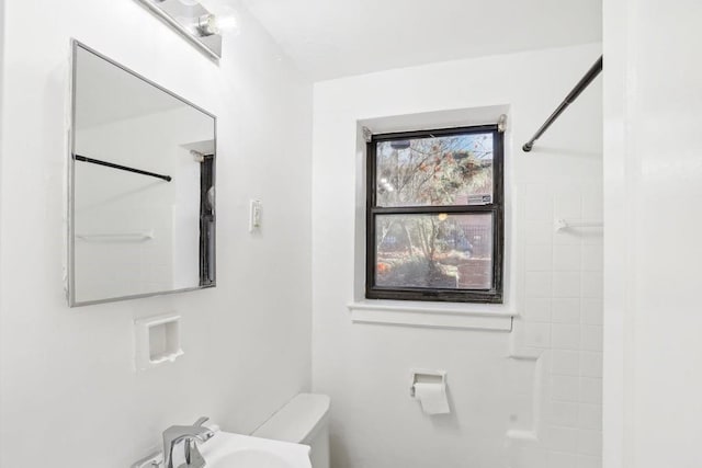 bathroom featuring toilet, walk in shower, and sink