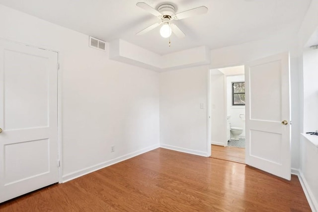 unfurnished bedroom featuring wood-type flooring, connected bathroom, and ceiling fan