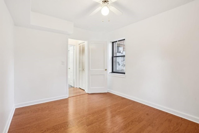 empty room featuring ceiling fan, baseboards, and wood finished floors