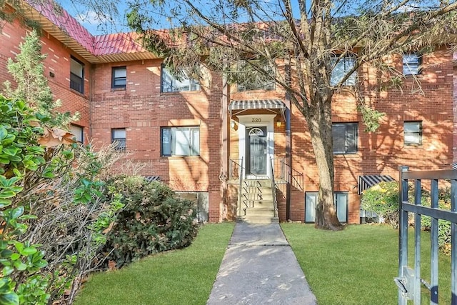 townhome / multi-family property featuring a tiled roof, brick siding, and a front yard