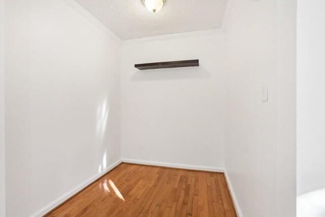 unfurnished room featuring ornamental molding, a textured ceiling, baseboards, and wood finished floors