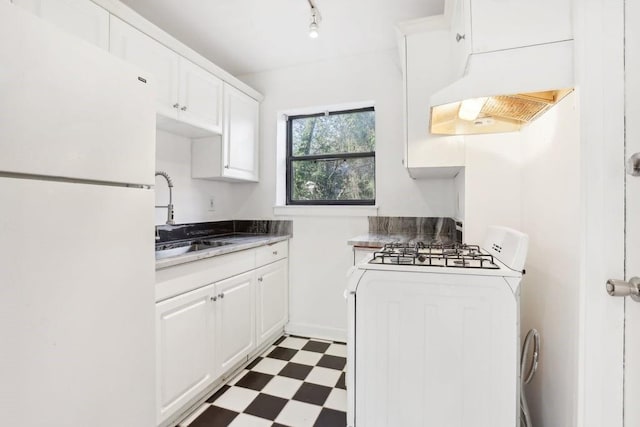 kitchen featuring white appliances, a sink, white cabinets, and tile patterned floors