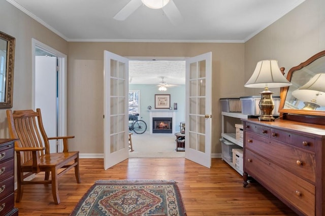 living area featuring french doors, ceiling fan, ornamental molding, and light wood-type flooring