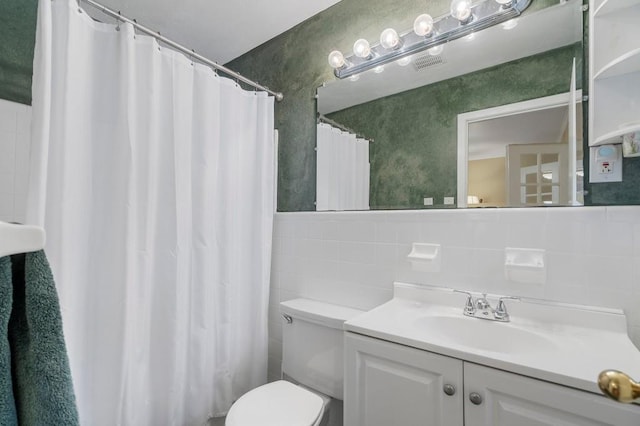 bathroom with walk in shower, vanity, toilet, and tile walls