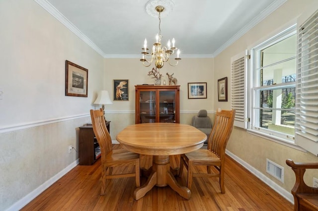 dining area featuring crown molding, a chandelier, and hardwood / wood-style floors