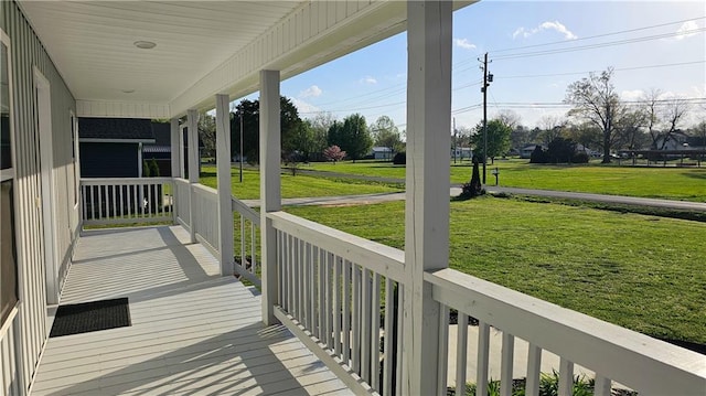 wooden terrace with a porch and a lawn