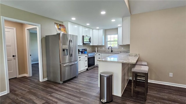 kitchen with white cabinetry, a kitchen breakfast bar, a peninsula, and stainless steel appliances
