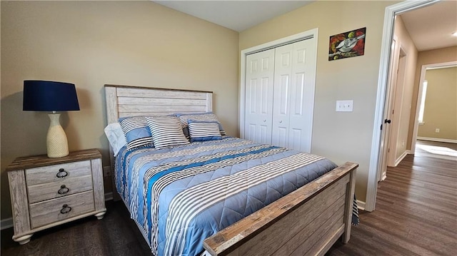 bedroom with a closet, dark wood-style flooring, and baseboards