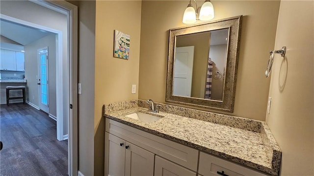 bathroom with wood finished floors, vanity, and baseboards