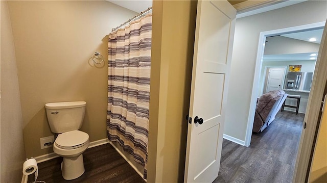 bathroom featuring toilet, a shower with shower curtain, wood finished floors, and baseboards