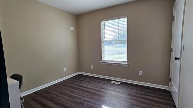 empty room featuring dark wood-style flooring, baseboards, and visible vents