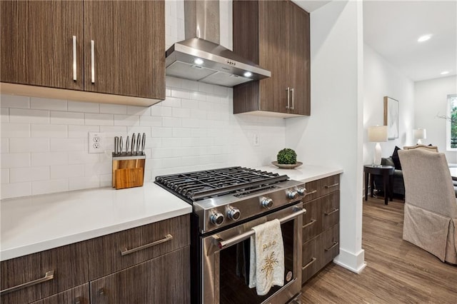 kitchen with hardwood / wood-style floors, backsplash, high end stainless steel range, and wall chimney range hood